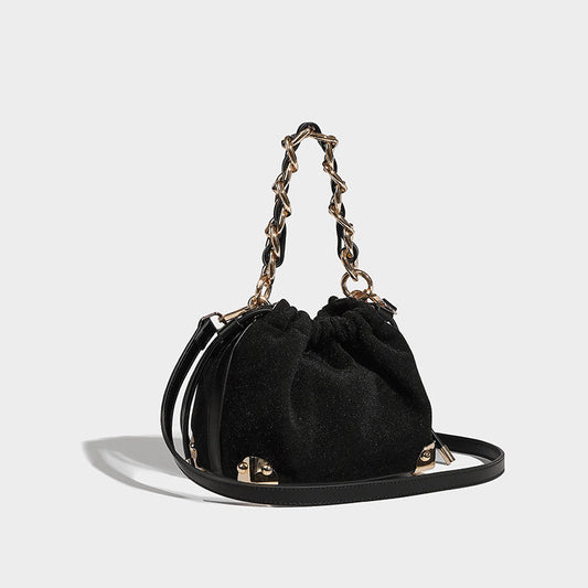 Black handbag with gold chain handle on a light gray background