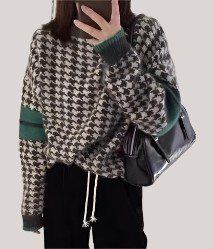 Person wearing a houndstooth pattern sweater with green accents, holding a black bag.
