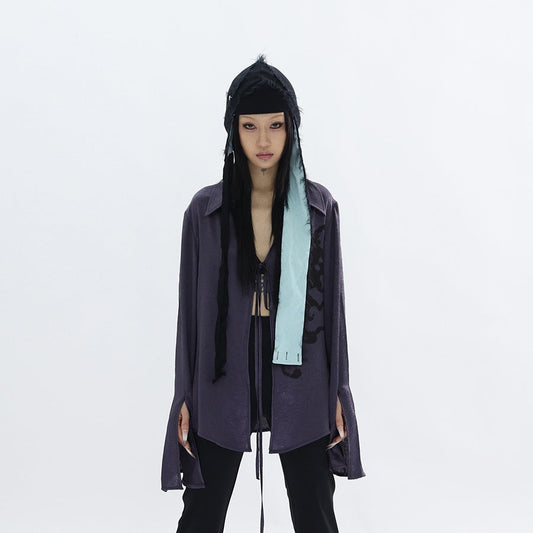 Person wearing a dark outfit with a hood and scarf on a white background