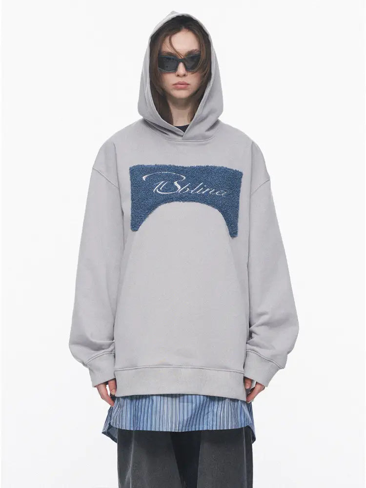 Person wearing a gray hoodie with a blue logo on a white background