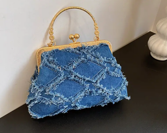 Blue textured handbag with gold handle on a dark surface