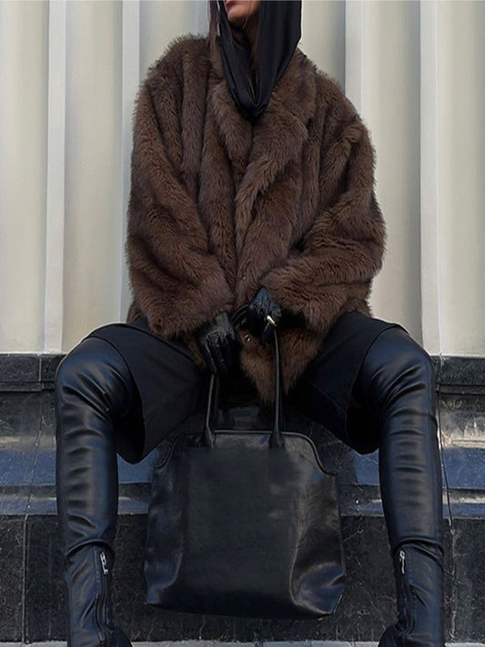Person wearing a brown fur coat and black leather pants sitting on steps.