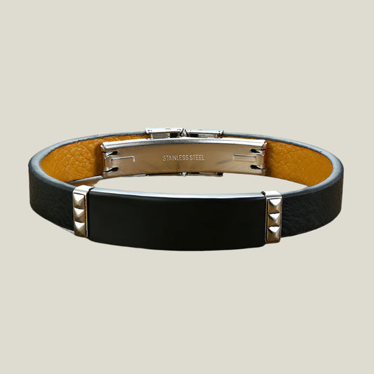 Black leather bracelet with stainless steel clasp on a wooden surface