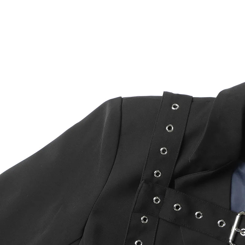 Close-up of a black garment with silver eyelet details on a white background