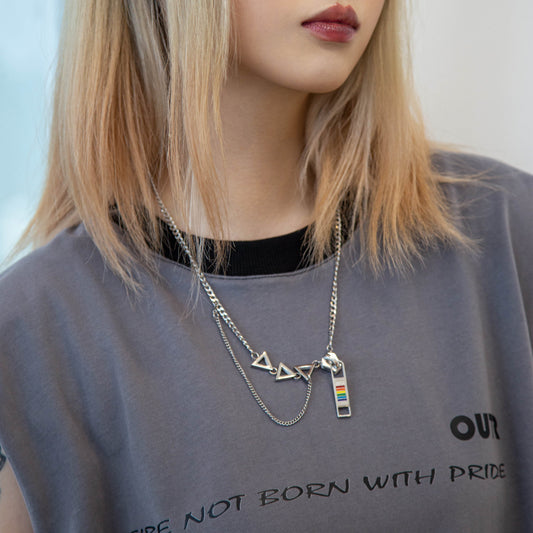 Person wearing a gray t-shirt with text and a necklace with a rainbow pendant.