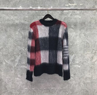 Plaid patterned sweater on a hanger against a gray background