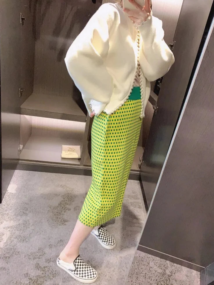 Person wearing a white hoodie and green patterned pants in a room.