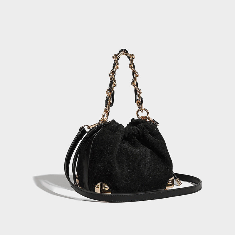 Black handbag with gold chain handle on a light gray background
