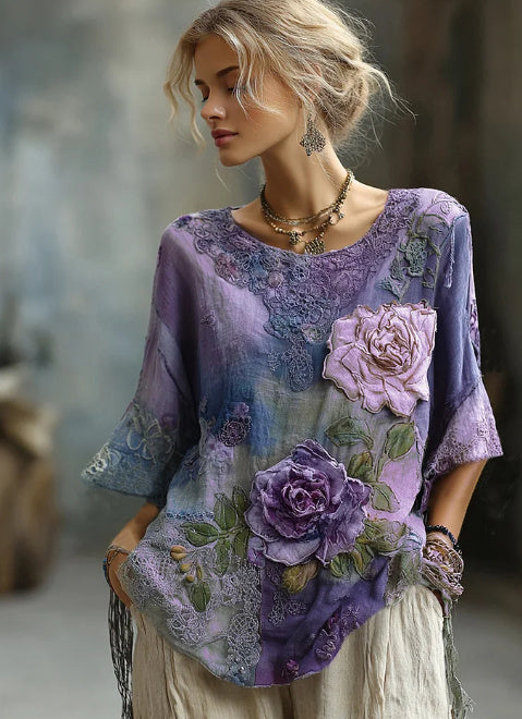 Woman wearing a purple embroidered top with floral designs against a blurred background