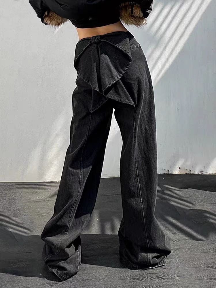 Person wearing black wide-leg pants with a ruffled top section against a neutral background