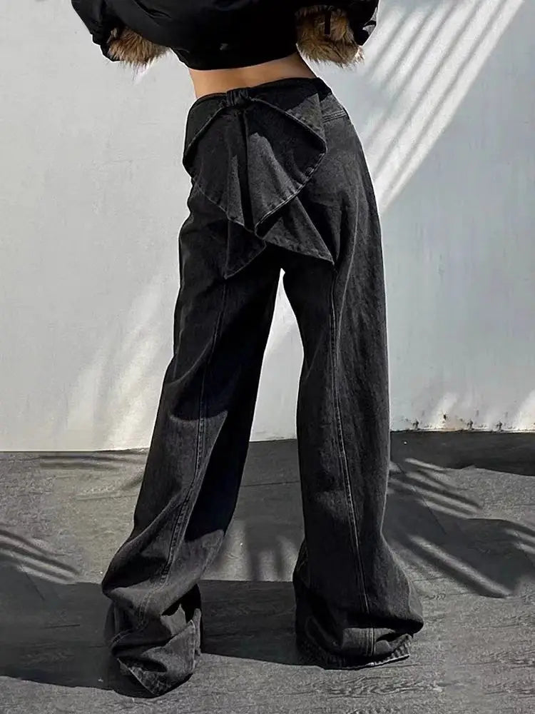 Person wearing black wide-leg pants with a ruffled top section against a neutral background