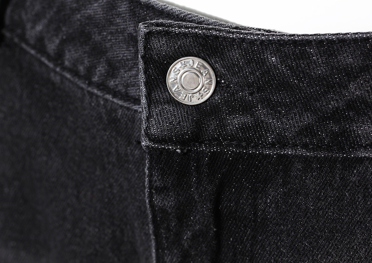 Close-up of a black denim button on a dark background