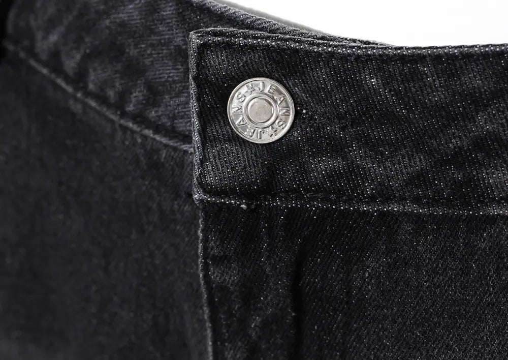 Close-up of a black denim button on a dark background