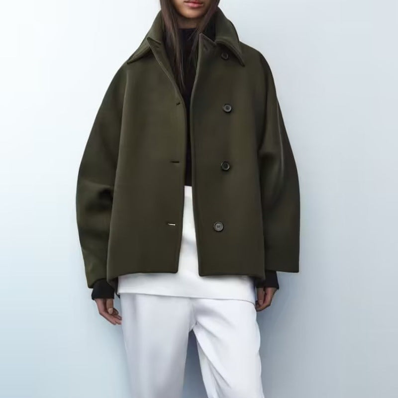 Person wearing a green coat and white pants against a light gray background