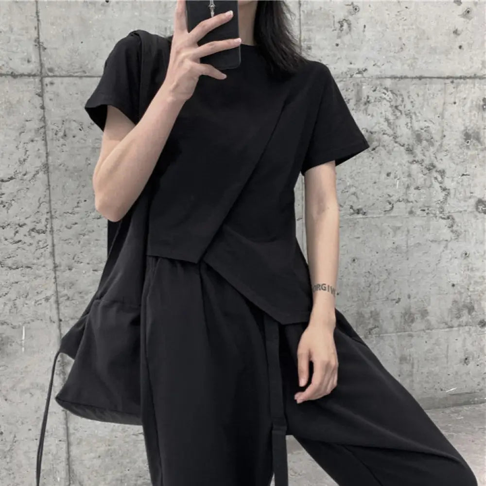 Person wearing a black outfit against a concrete wall.