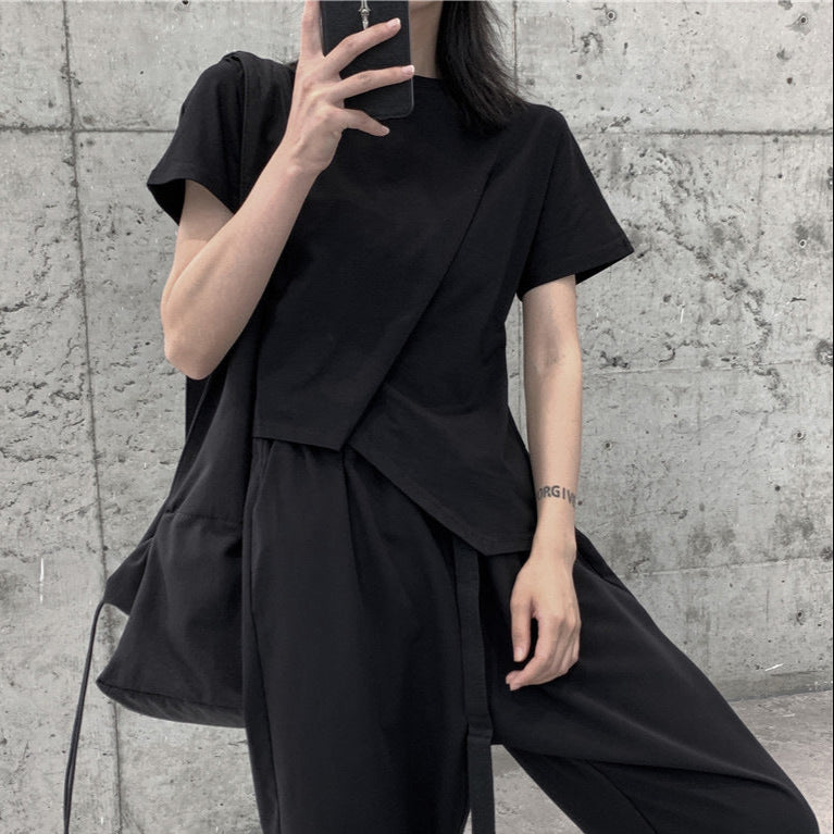 Person wearing a black outfit against a concrete wall.