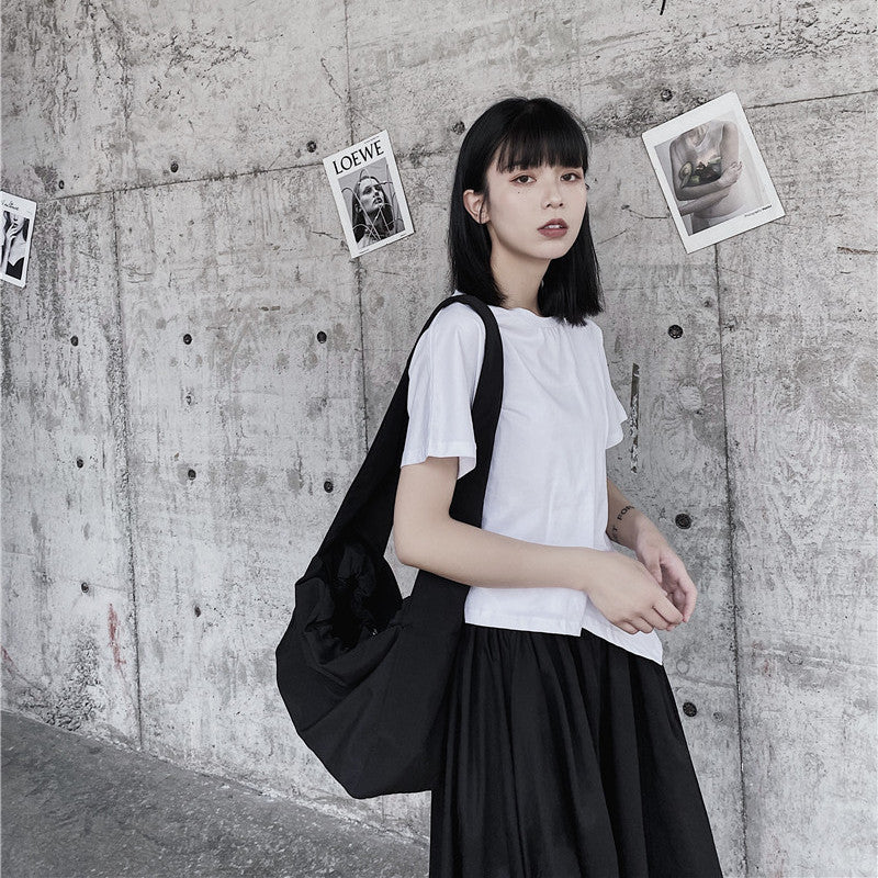 Woman with a black backpack standing against a textured wall with pinned photos