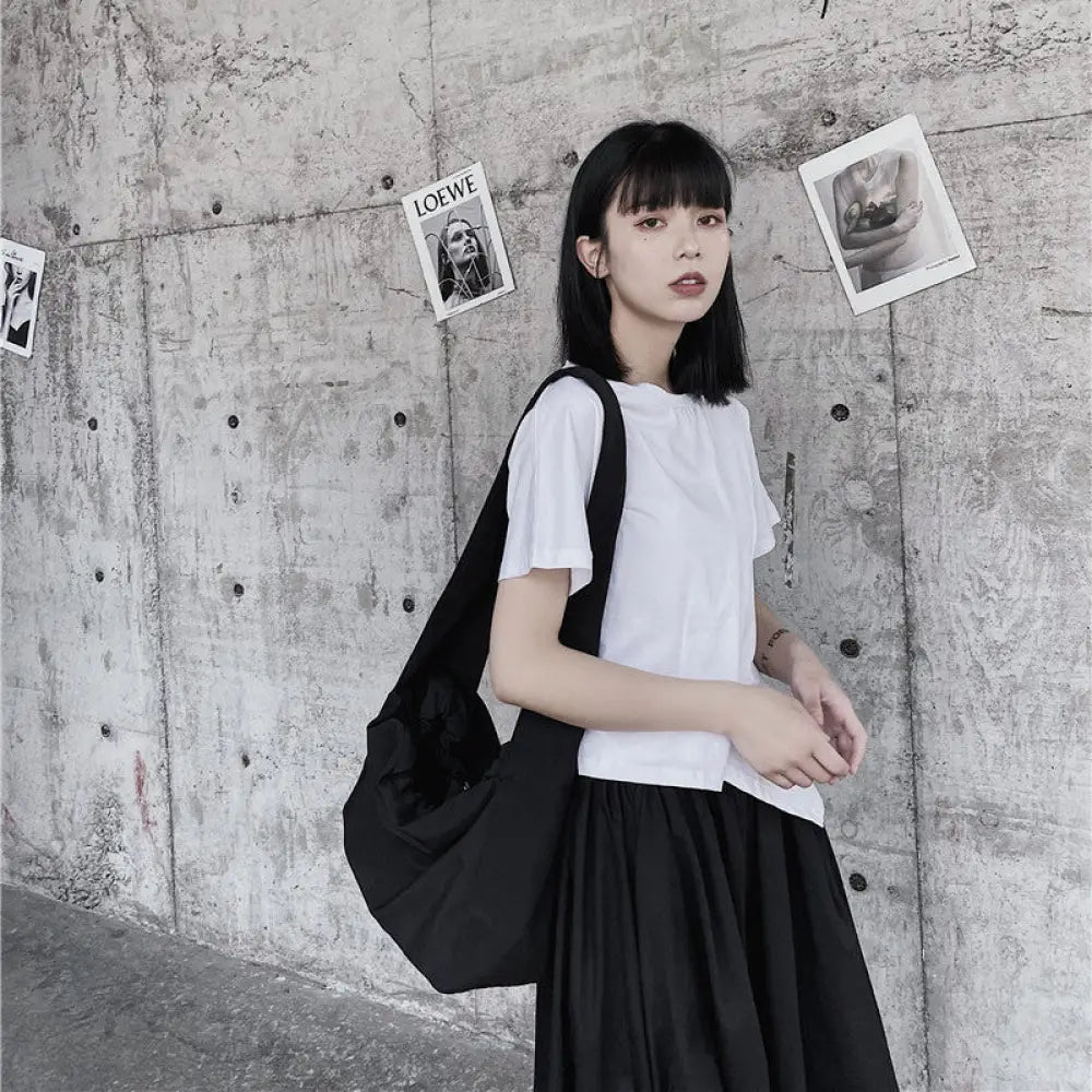 Woman with a black backpack standing against a textured wall with pinned photos