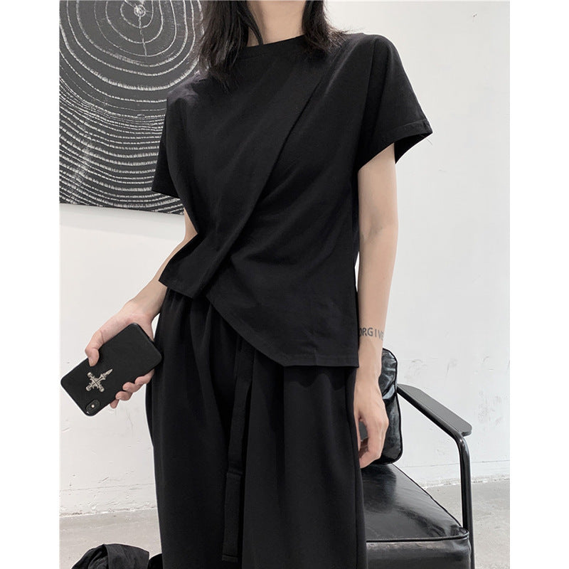 Person wearing a black outfit holding a phone and a bag against a minimal background