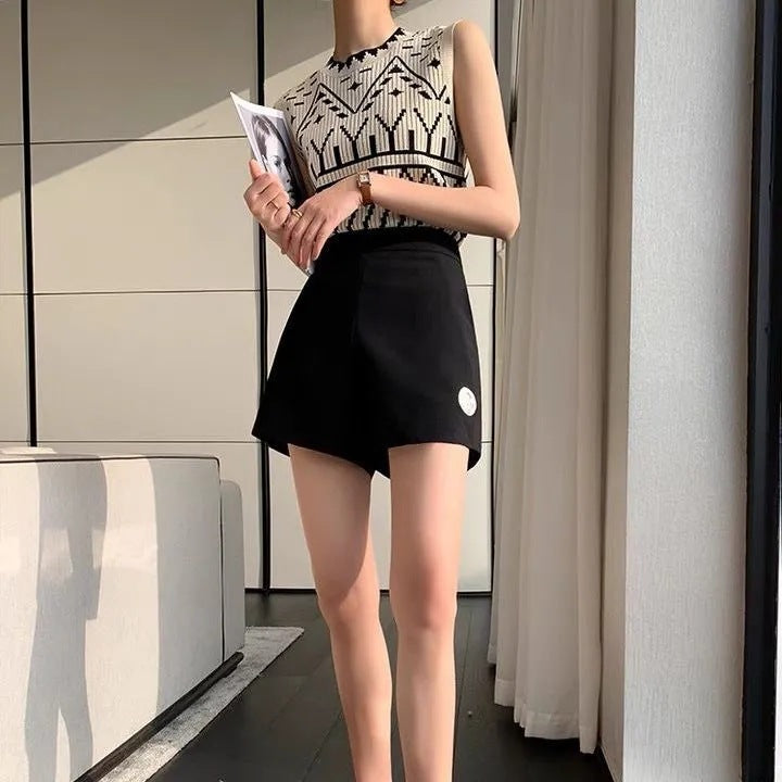 Woman wearing a sleeveless patterned top and black skirt holding a magazine indoors.