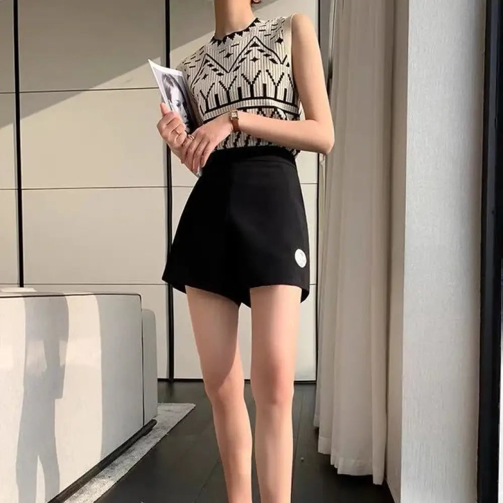 Woman wearing a sleeveless patterned top and black skirt holding a magazine indoors.