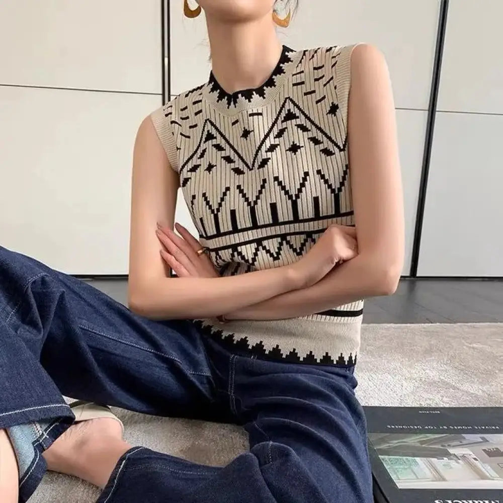 Person wearing a sleeveless patterned top and blue jeans sitting on the floor.