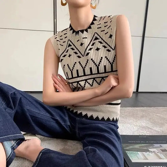 Person wearing a sleeveless patterned top and blue jeans sitting on the floor.