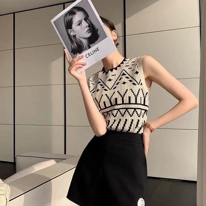 Person wearing a patterned sleeveless top and black skirt, holding a Celine magazine.