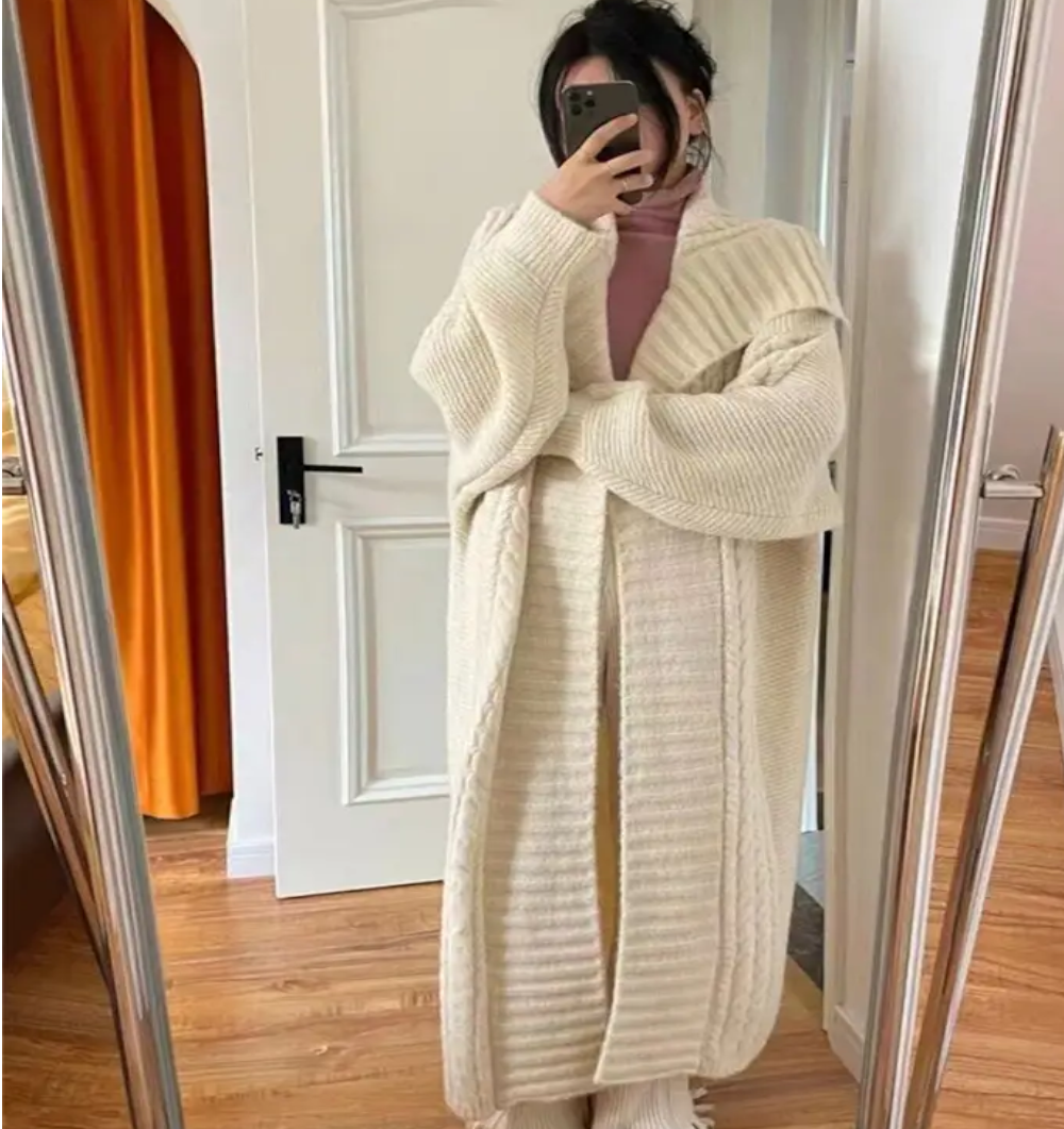 Person wearing a long cream cardigan in front of a mirror.