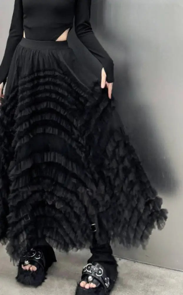 Person wearing a black ruffled skirt with a plain background