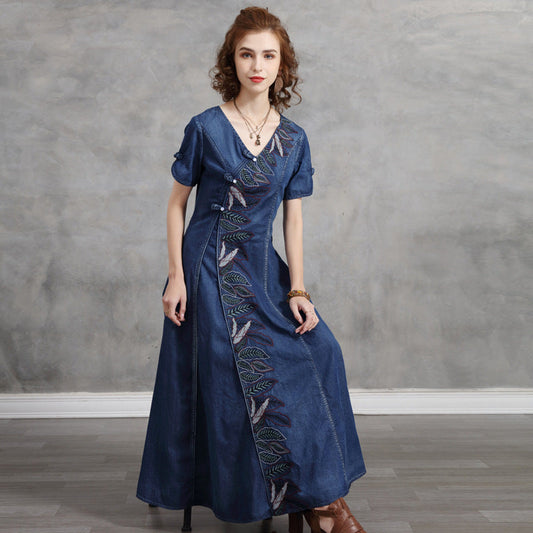 Woman wearing a blue dress with embroidery against a gray background
