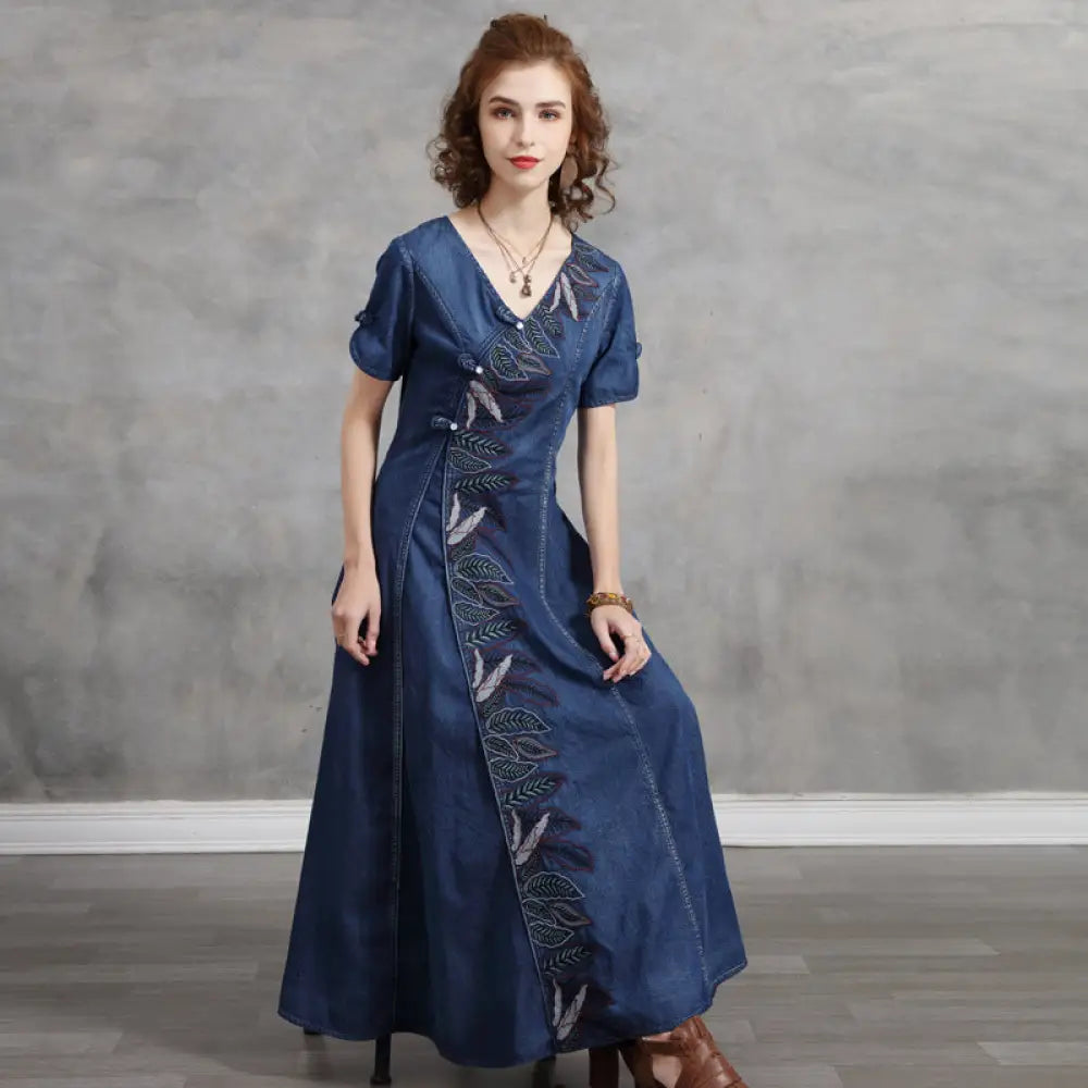Woman wearing a blue dress with embroidery against a gray background