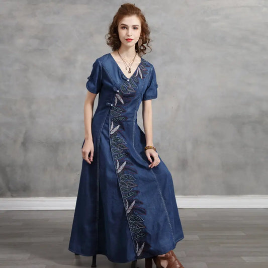 Woman wearing a blue dress with embroidery against a gray background
