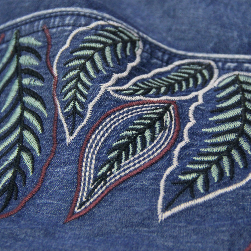 Close-up of embroidered leaves on a blue fabric background