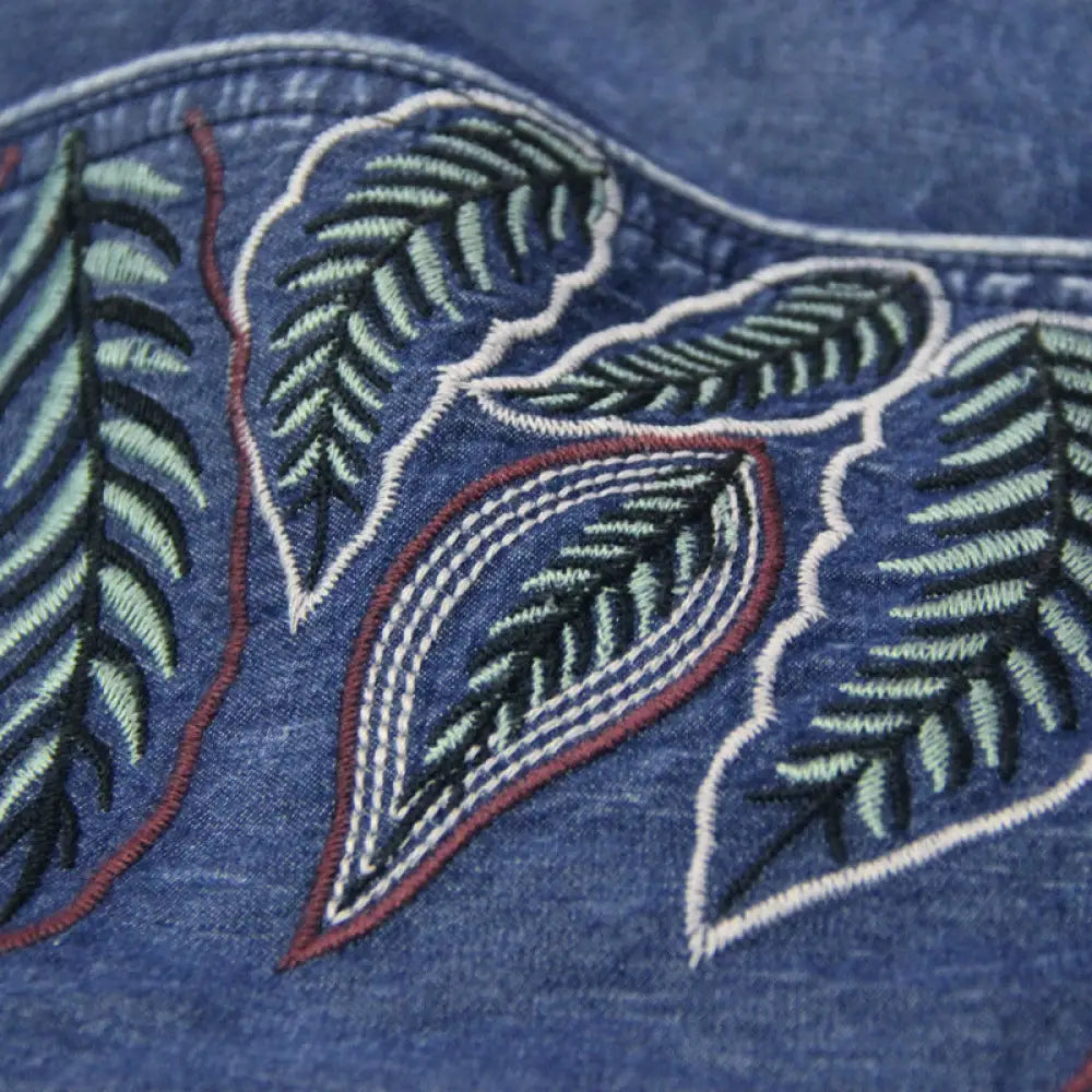Close-up of embroidered leaves on a blue fabric background