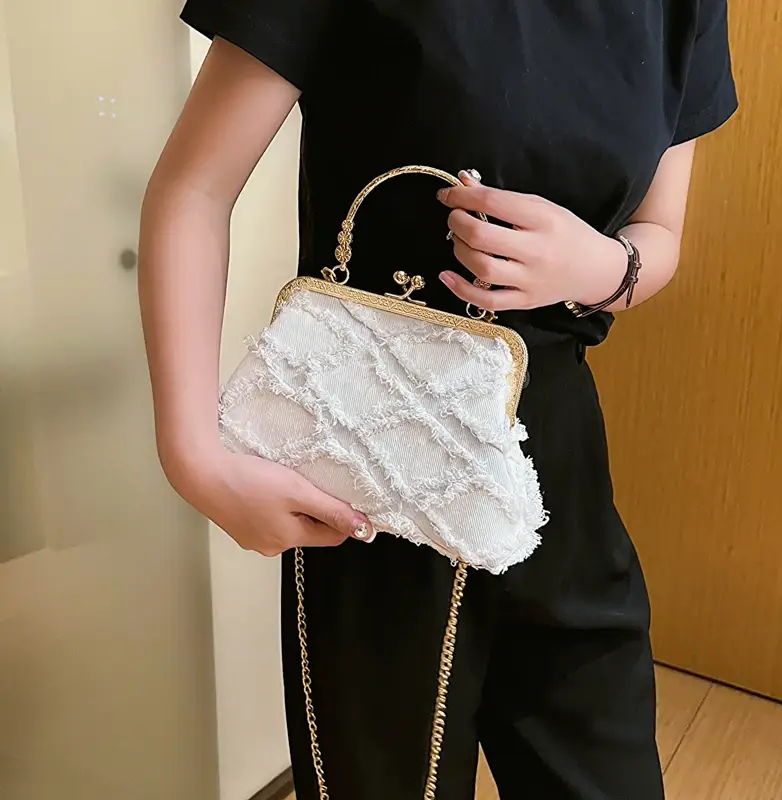 Person holding a white lace handbag with gold chain strap against a neutral background