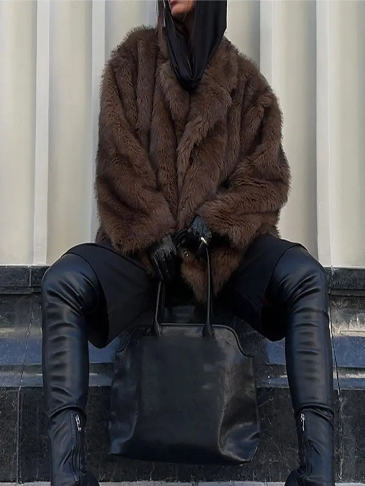 Person wearing a brown fur coat and black leather pants sitting on steps.