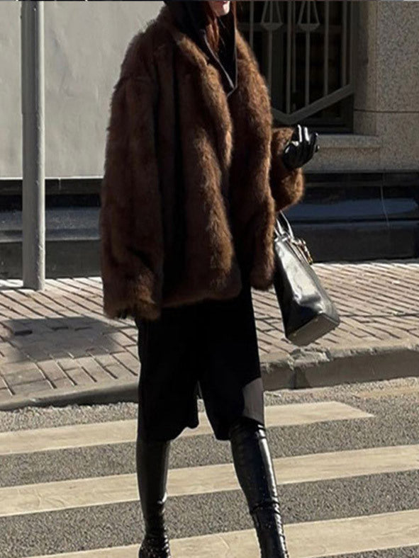 Person wearing a brown fur coat and black knee-high boots crossing a street.