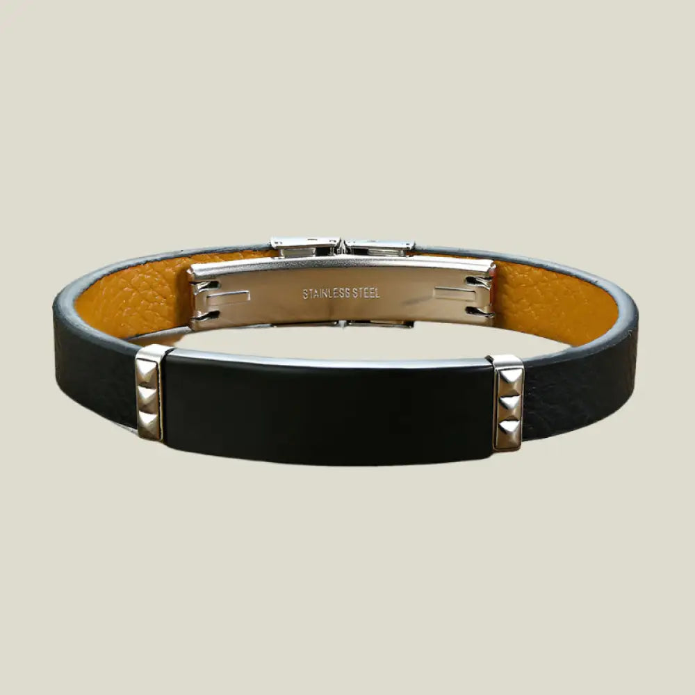 Black leather bracelet with stainless steel clasp on a wooden surface