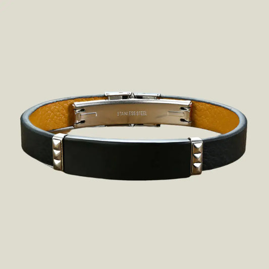 Black leather bracelet with stainless steel clasp on a wooden surface