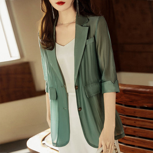 Woman wearing a green blazer over a white top in an indoor setting