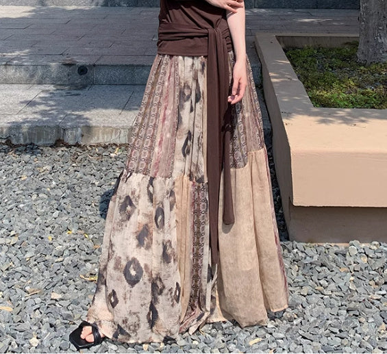 Person wearing a long, patterned skirt with a brown top outdoors.