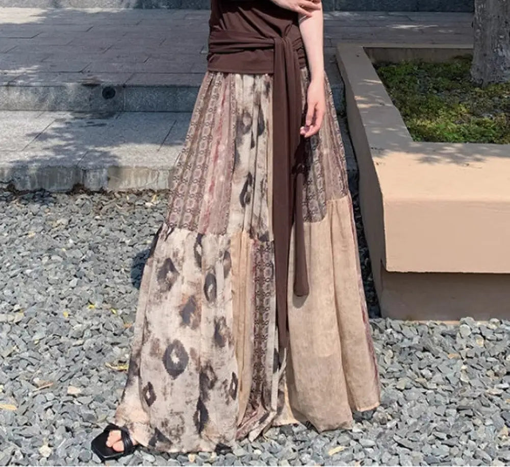 Person wearing a long, patterned skirt with a brown top outdoors.