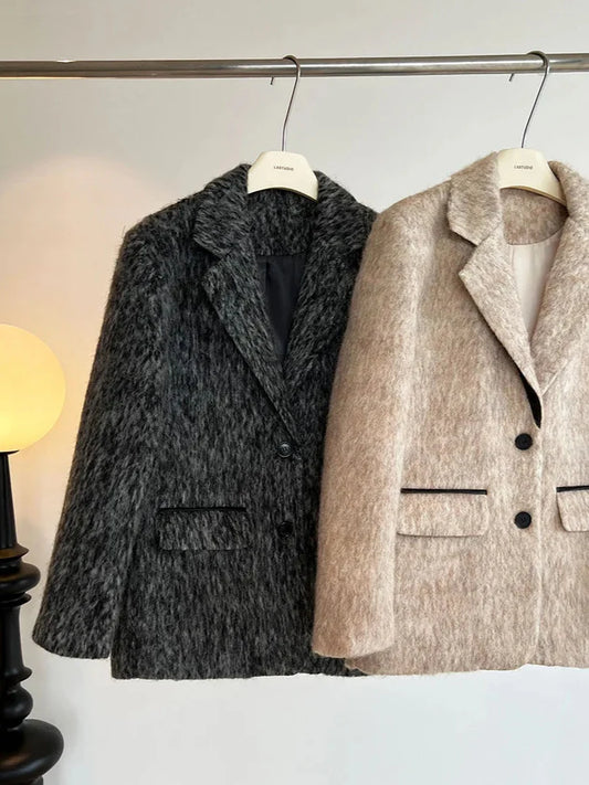Two coats hanging on a rack against a white wall.