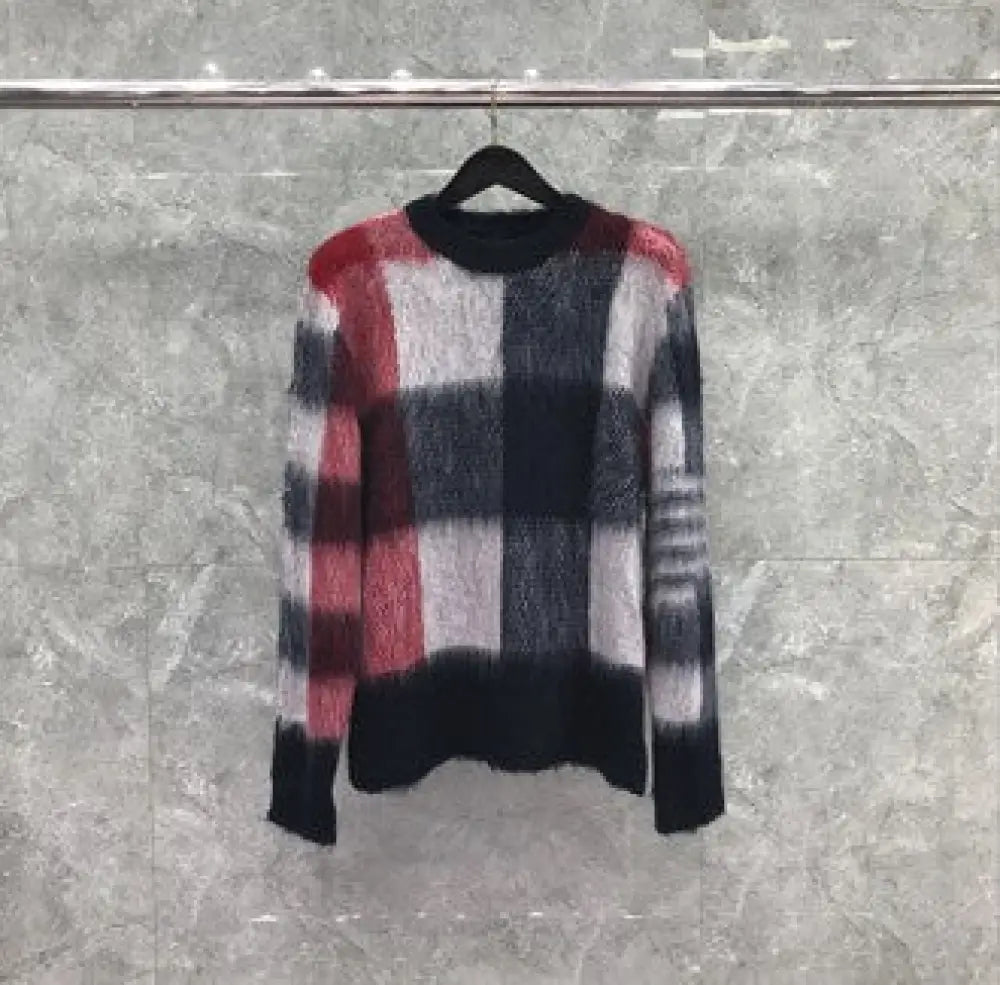 Plaid patterned sweater on a hanger against a gray background