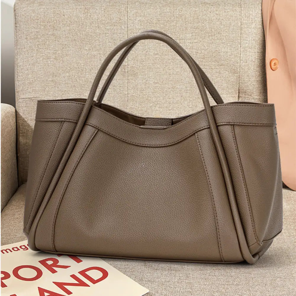 Brown handbag on a textured surface with a magazine underneath