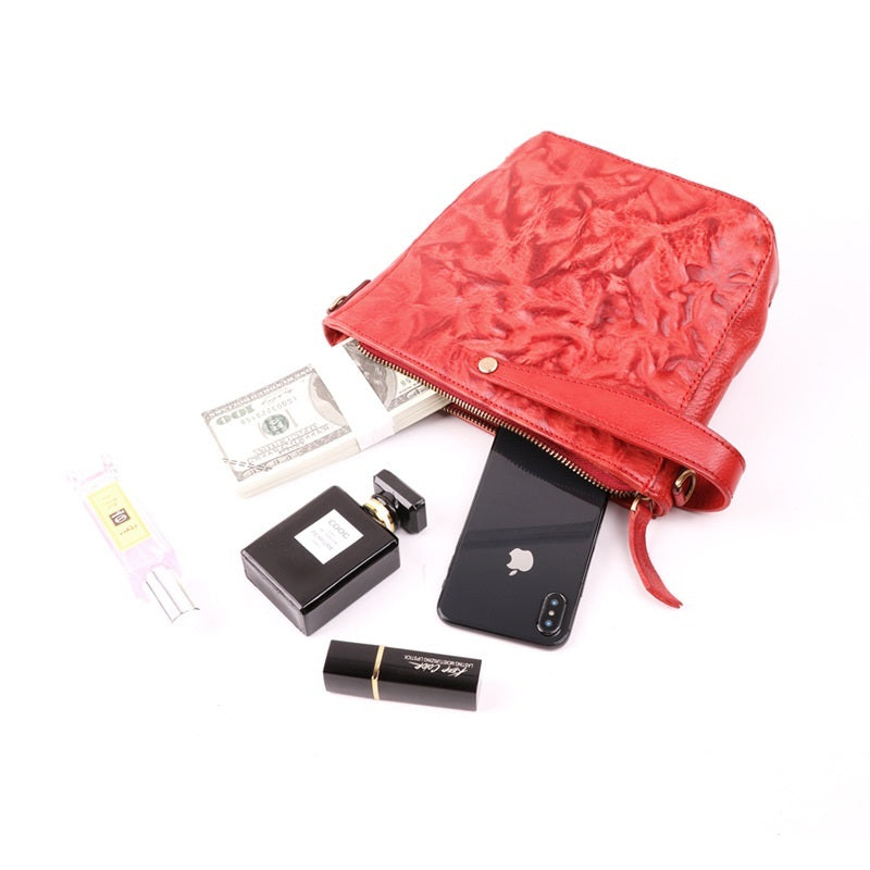 Red pouch with various items including a phone, money, and lip balm on a white background