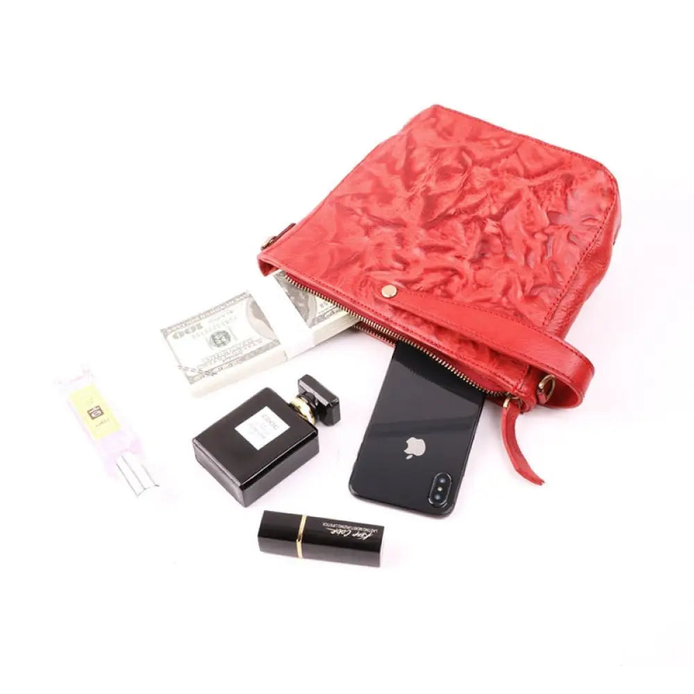 Red pouch with various items including a phone, money, and lip balm on a white background