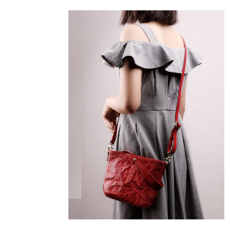 Person wearing a gray dress with a red handbag on a plain background